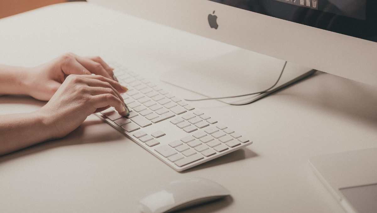 Hands typing on an Apple keyboard